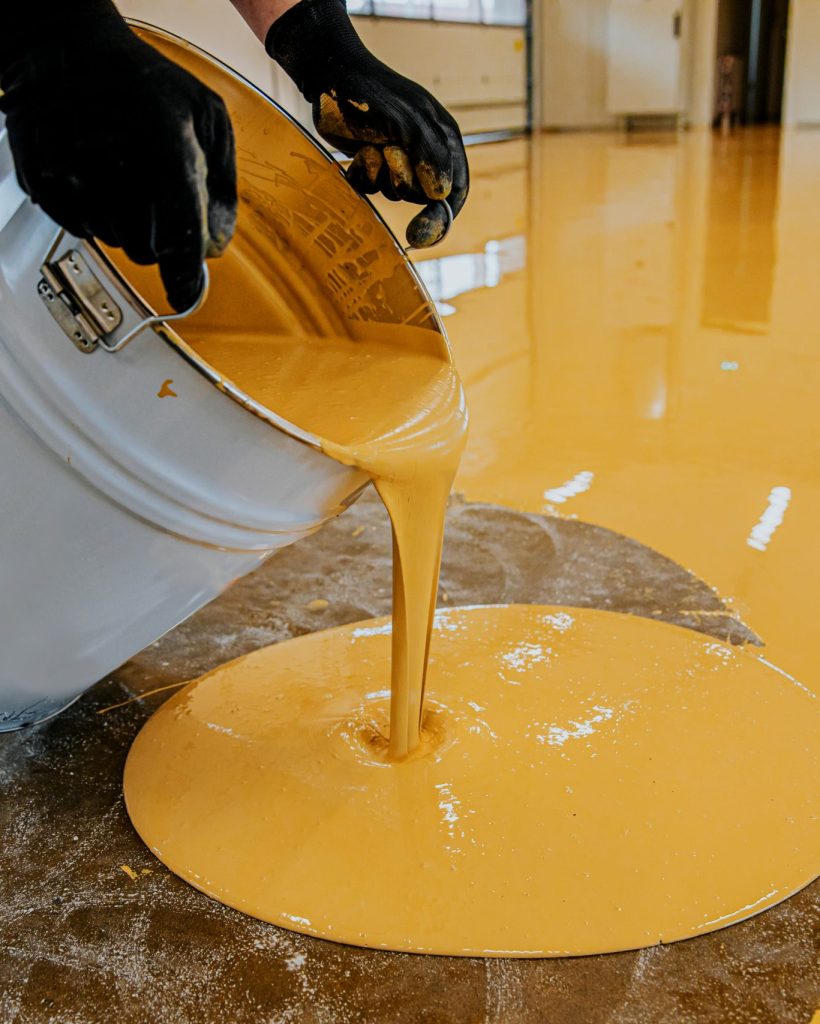 A construction worker apply epoxy resin in an industrial hall