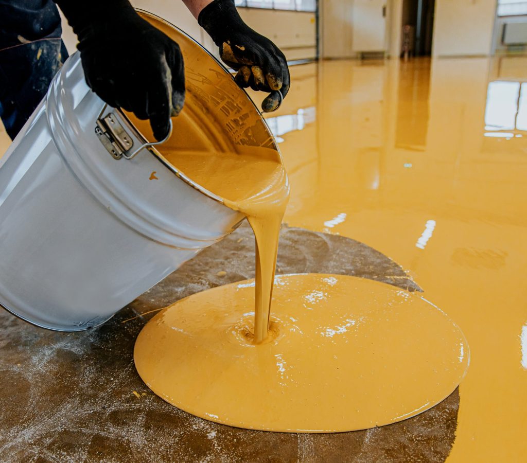 A construction worker apply epoxy resin in an industrial hall