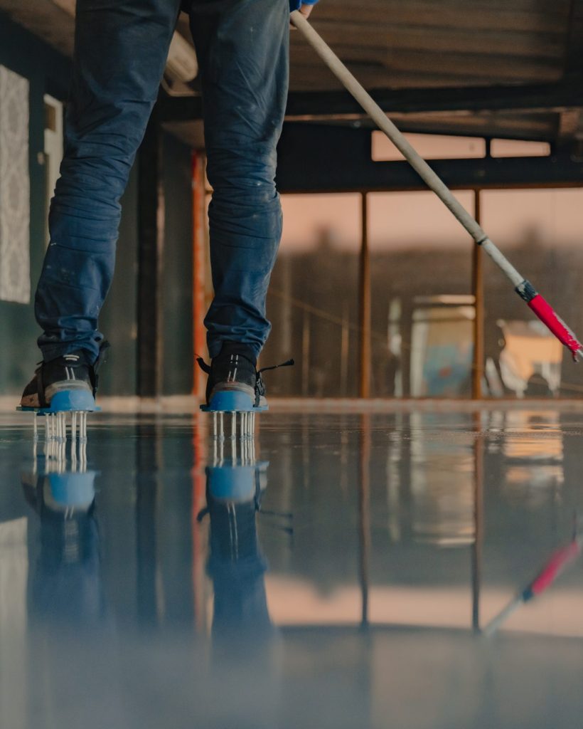 The worker applies gray epoxy resin to the new floor